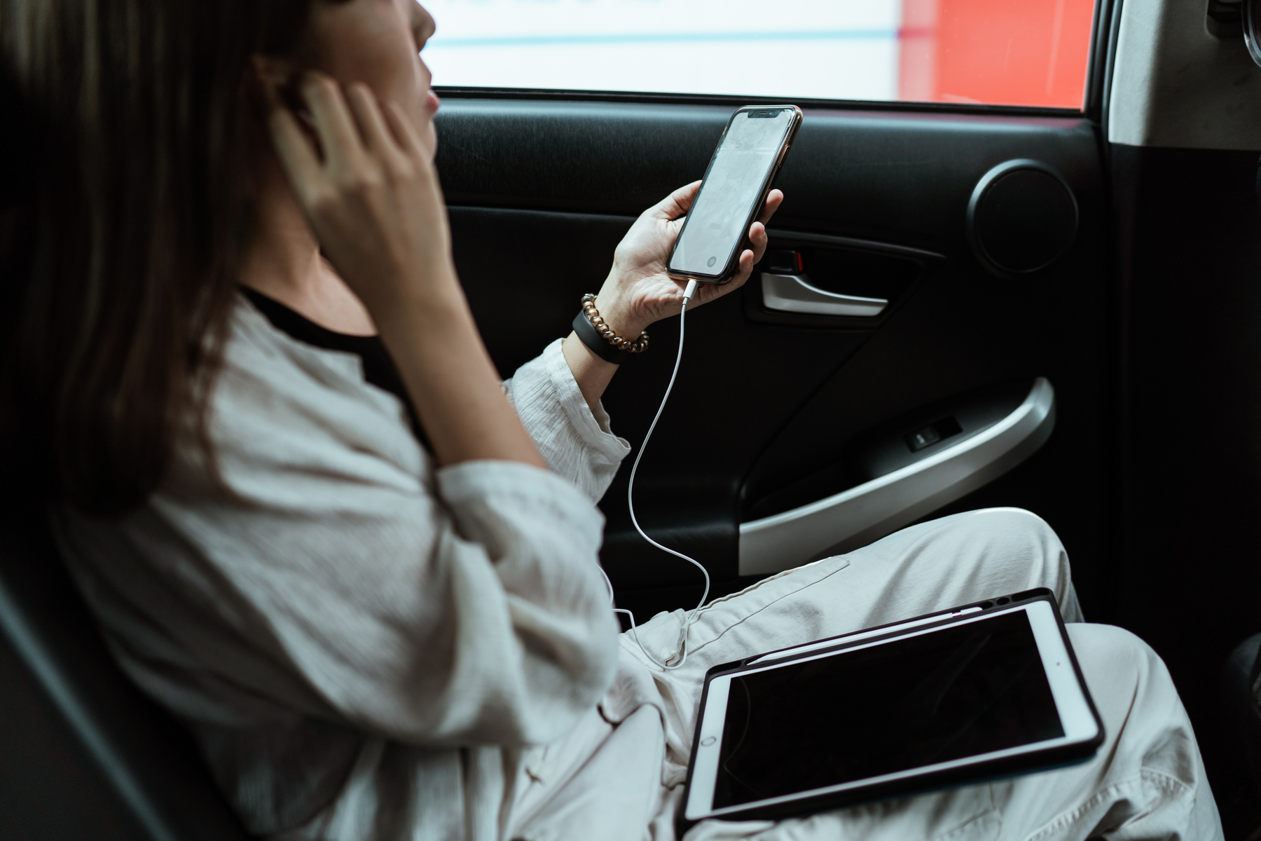 Crop unrecognizable freelancer listening to music via earphones on smartphone